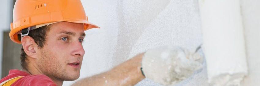 Ein Maler streicht eine Wand mit einer Farbrolle 