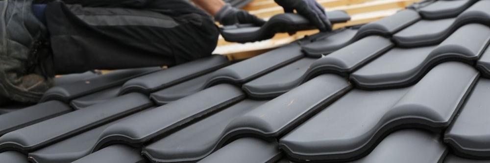 Ein Dachdecker verlegt schwarze Ziegelsteine